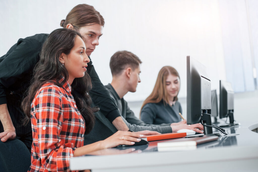 Students learning on computers in a modern digital marketing institute classroom with trainer guidance and professional computer education environment.
